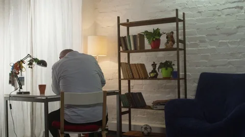 Thoughtful senior man in the living room. Sad old man sitting at the table Stock Footage