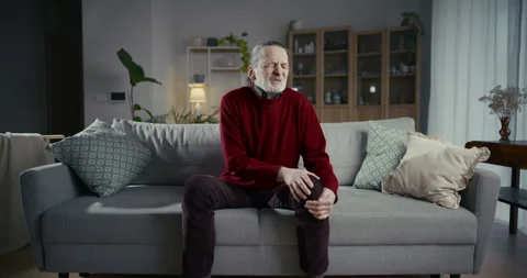 Thoughtful senior man sitting alone on a sofa in a modern living room Stock Footage 336280265