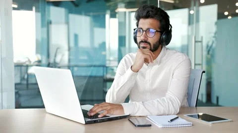 Thoughtful serious IT specialist coder in wireless headphones typing on laptop  Stock Footage 248605756