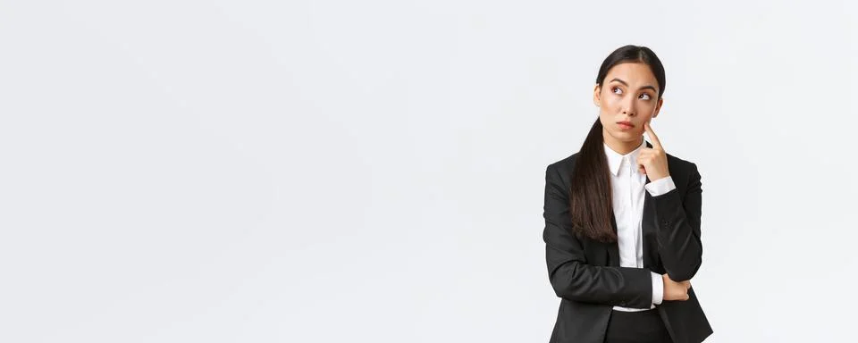 Thoughtful serious-looking asian female manager, office worker in suit thinking Stock Photos