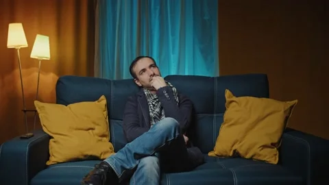 Thoughtful serious man sits on sofa thinking of inspiration search solution Stock Footage 170435247