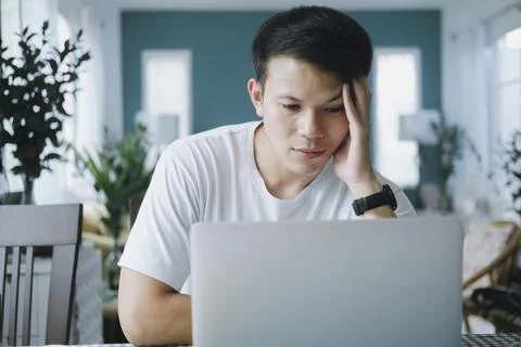 Thoughtful serious young man solving online problem doing resear Foto stock