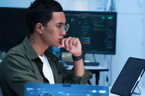 Thoughtful Software Developer Reviewing Code on Laptop Stock Photos