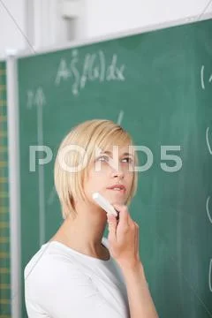 Thoughtful student with hand on chin solving sums on chalkboard Stock Photos