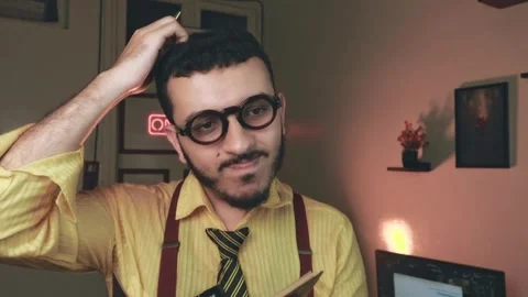 Thoughtful Vlogger Adjusting Glasses, Warm Cinematic Room Video stock 318593172