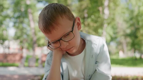 Thoughtful white boy relaxing outside. Caucasian youth sitting pensively in Stock Footage 333087153