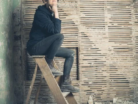 Thoughtful womamn sitting on stepladder Stock-Fotos