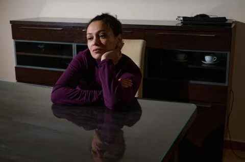 Thoughtful Woman At The Dining Table In A Quiet Room Reflecting On Life Stock Photos