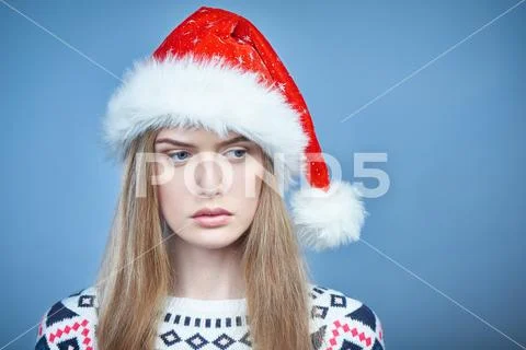 Thoughtful woman wearing Santa hat looking aside Stock Photos