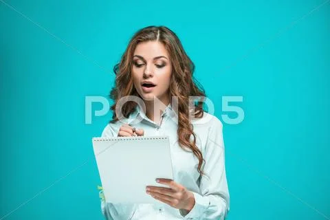 The thoughtful young business woman with pen and tablet for notes on blue Stock Photos