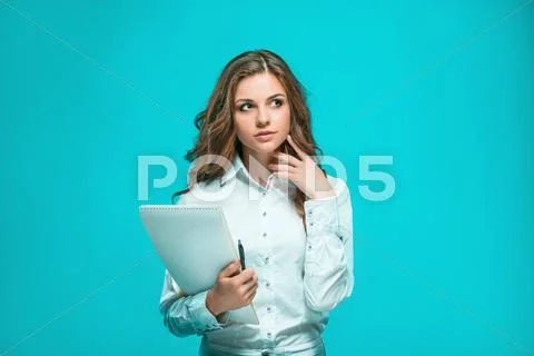 The thoughtful young business woman with pen and tablet for notes on blue Stock Photos