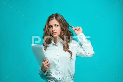 The thoughtful young business woman with pen and tablet for notes on blue Stock Photos