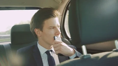 Thoughtful young businessman going in the car and using the smartphone 4K Stock Footage