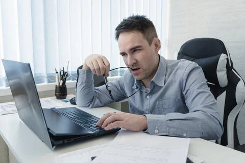 A thoughtful young handsome guy writes a program in a bright white office. .. 스톡 사진