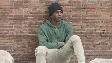 Thoughtful young immigrant sitting alone on the ground thinking  Stock Footage 240331537