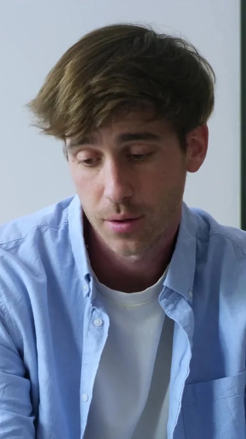 Thoughtful young man with a sad and concerned expression talking about his Vídeos de archivo 345114050