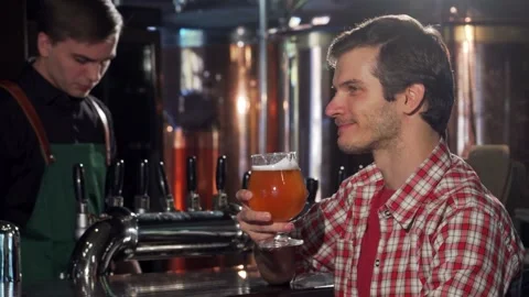 Thoughtful young man savoring a refreshing beer at a cozy pub Video stock 311177253