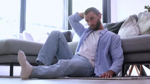 Thoughtful young man sitting alone on the floor, feeling worried and stressed Stock Footage 345078951