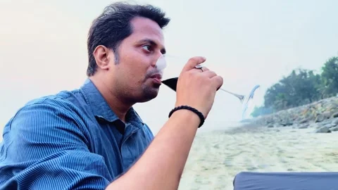 Thoughtful young man sitting on the beach drinking red wine on the table Stock Footage 263440438