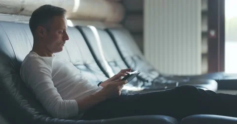 Thoughtful young man is sitting on sofa in room, looking for information on Stock Footage 197816635
