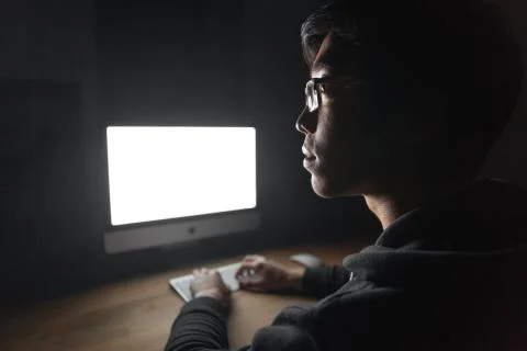 Thoughtful young man using blank screen computer in dark room Stock Photos