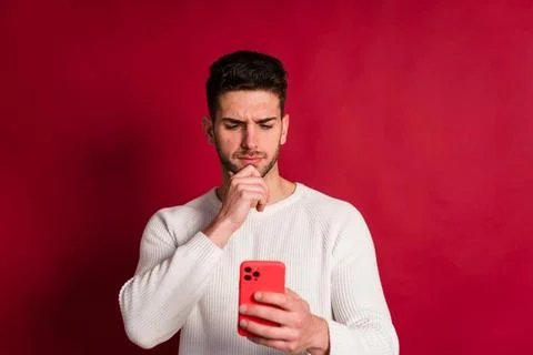 Thoughtful young man using smartphone with serious facial expression Stock Photos