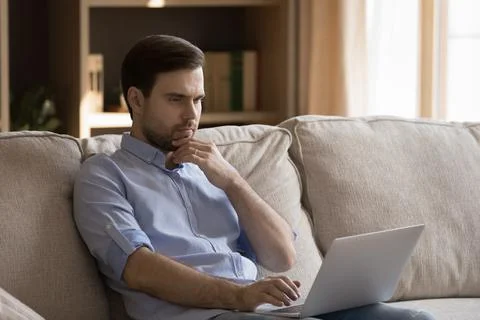 Thoughtful young man working on computer at home. Stockfoto's