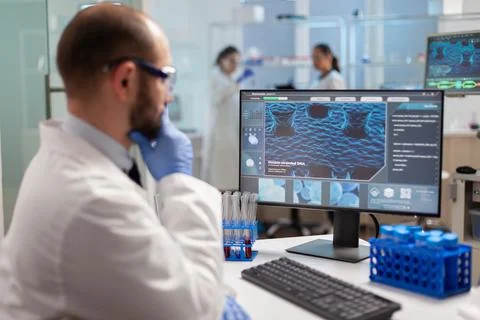 Thoughtfull doctor analyzing virus evolution on computer screen Stock Photos