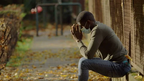 Thoughts, concern - black man wearing the mask sitting on the wall thinking Video stock 143482913