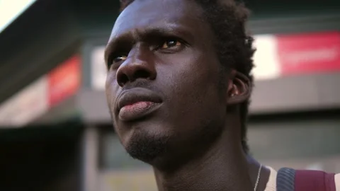 Thoughts, concern -  young black man in the street looks away thinking Stock Footage 240327004
