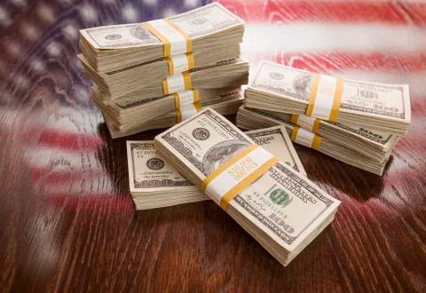 Thousands of Dollars Stacked with Reflection of American Flag on Wooden Table Foto stock