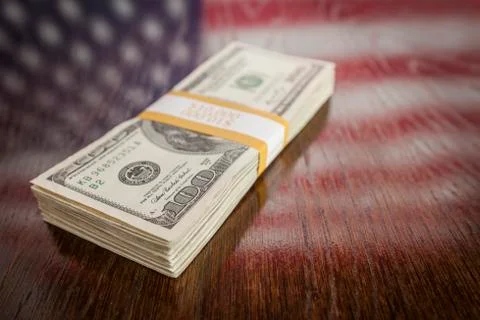 Thousands of Dollars Stacked with Reflection of American Flag on Wooden Table Stock-Fotos