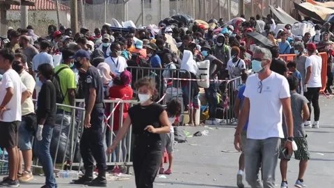 Thousands of migrants in Lesbos queue to enter new camp after devastating fire Stock Footage 272974306