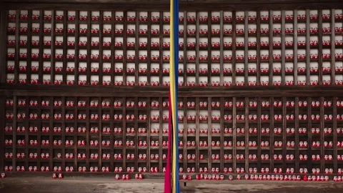 Thousands of red daruma dolls filling wooden grid shelves at Katsuoji Temple Stock Footage 337777227