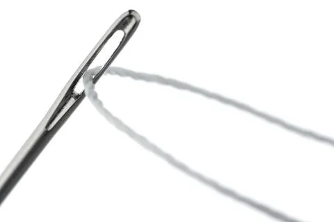 Thread inserted through the needle's eye, photographed on a white background Foto stock