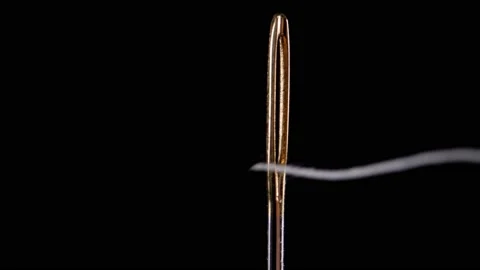 Thread for sewing is threaded into the eye of a needle. Sewing needle. Stock-Footage 170023090