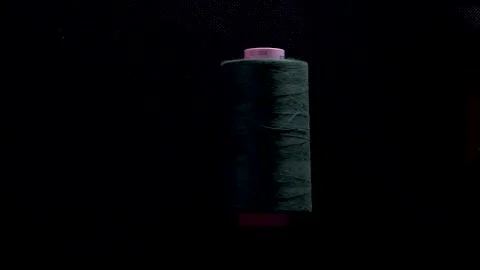 Thread spool on bobbin roll color on black background slow motion Stock Footage 267980446