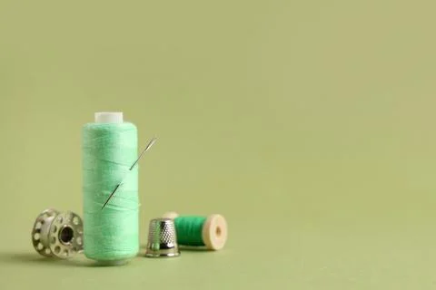 Thread spool with needle on green background, closeup Stock Photos