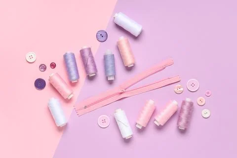 Thread spools with buttons and zipper on color background Stock Photos