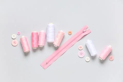 Thread spools with buttons and zipper on grey background Stock Photos