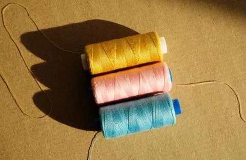 Thread spools in direct sunlight on a craft background, sewing concept Foto stock