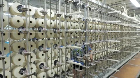 Thread spools hang on metal racks at textile factory, employee attaches threads Stock Footage 271616221