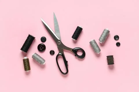 Thread spools with scissors and buttons on pink background Stock Photos