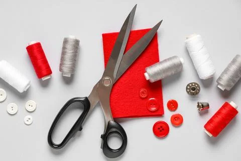 Thread spools with scissors, buttons, fabric and thimble on grey background Stock Photos