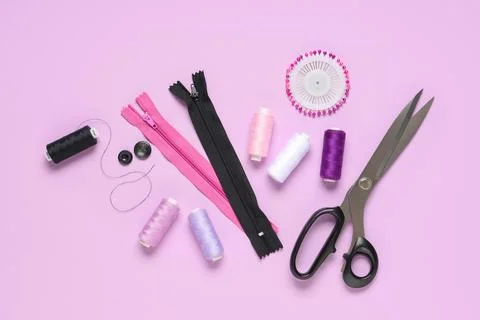 Thread spools with scissors, zippers and sewing pins on lilac background Stock Photos