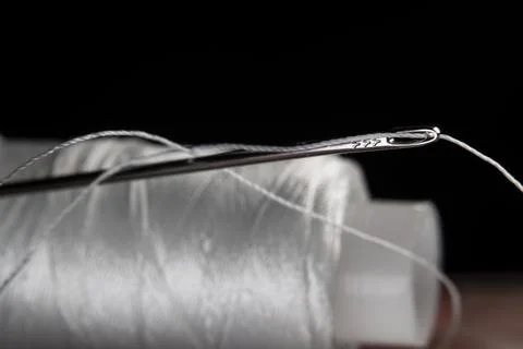 The thread is threaded through the eye of a sewing needle.Sewing and needlewo Stock Photos