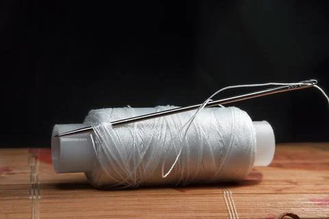 The thread is threaded through the eye of a sewing needle.Sewing and needlewo Stock Photos