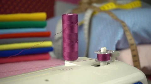 Thread is unwound from the reel during sewing to other coil in slow motion. Sewi Stock Footage 100199657