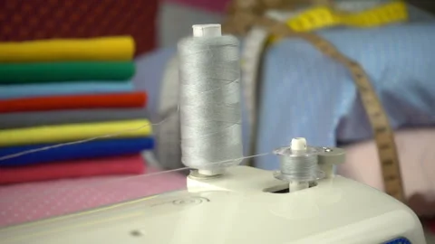 Thread is unwound from the reel during sewing to other coil in slow motion. Sewi Stock Footage 100199980