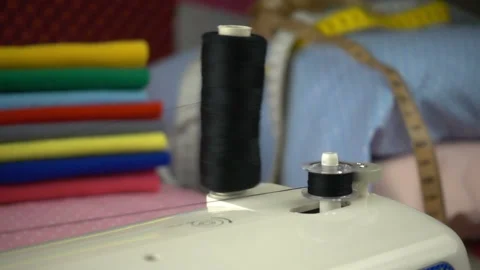 Thread is unwound from the reel during sewing to other coil in slow motion. Sewi Stock Footage 100200367